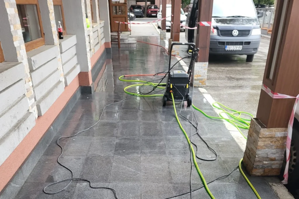 Trotoar ispred radnje pere se mašinom za visok pritisak i crevom za odvod